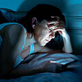 Woman Looking at Her Phone While in Bed
