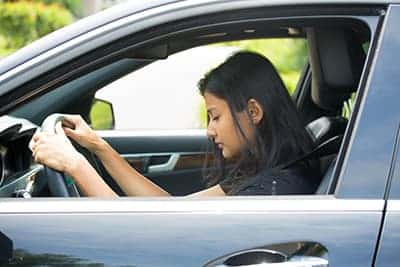 Woman asleep at wheel of car